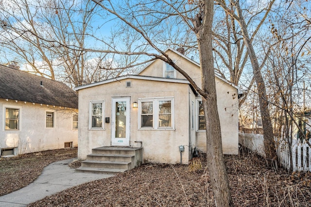 bungalow-style home featuring fence and stucco siding