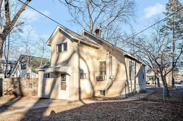 rear view of house with a chimney, fence, and stucco siding