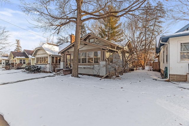 bungalow-style house featuring a chimney and stucco siding