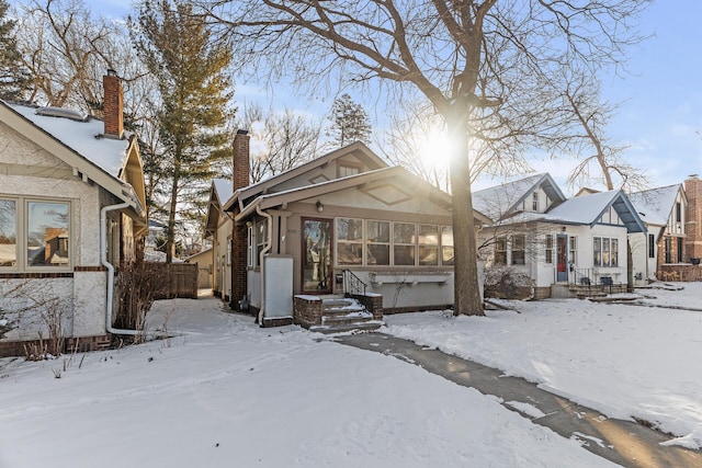 snow covered property featuring fence and a chimney