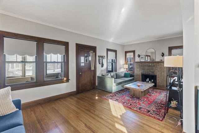 living room with a fireplace, crown molding, baseboards, and wood finished floors