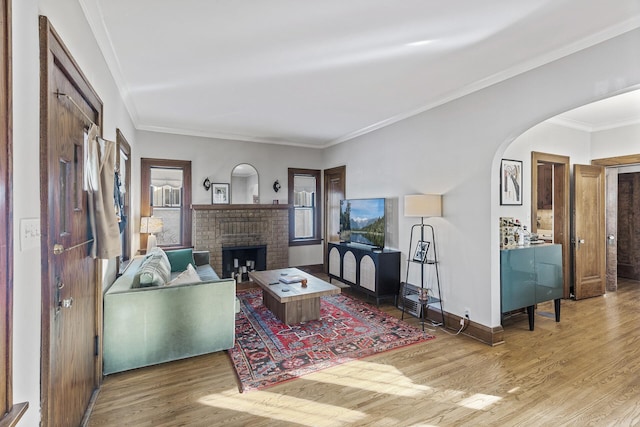 living area featuring baseboards, crown molding, arched walkways, and wood finished floors