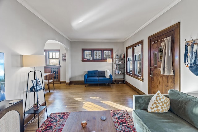 living room with arched walkways, baseboards, wood finished floors, and crown molding