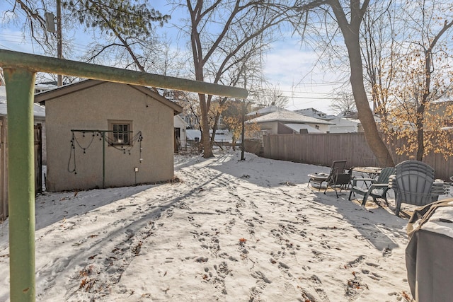 snowy yard with an outdoor fire pit and fence