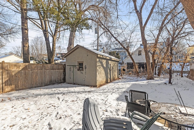 yard covered in snow featuring a storage unit, fence, and an outbuilding