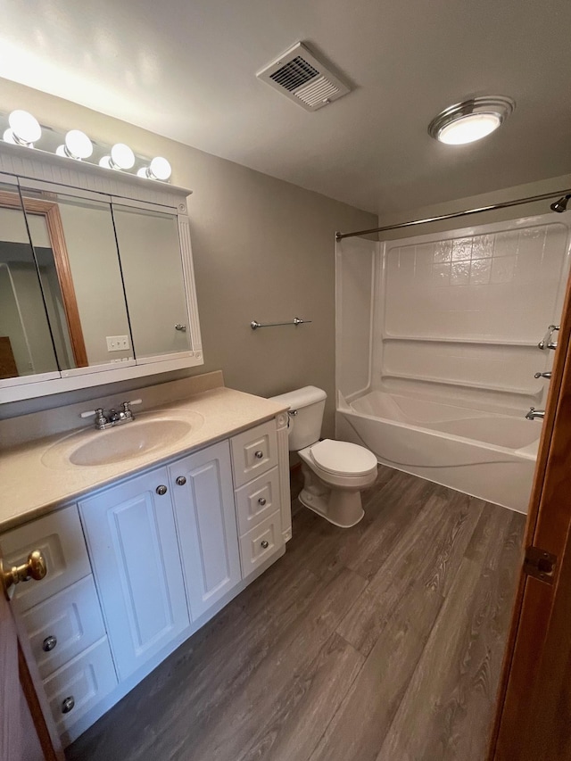 bathroom featuring toilet, wood finished floors, vanity, visible vents, and washtub / shower combination