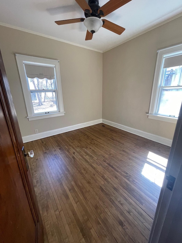 unfurnished room with baseboards, dark wood-type flooring, and crown molding