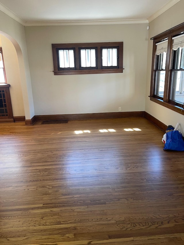 unfurnished room with ornamental molding, arched walkways, and dark wood-type flooring