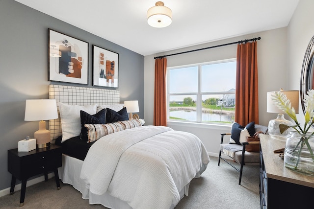 bedroom with carpet, a water view, and baseboards