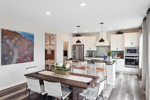 dining room featuring baseboards, wood finished floors, and recessed lighting