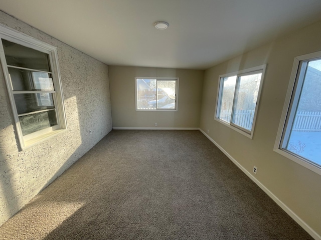 unfurnished room featuring carpet and baseboards