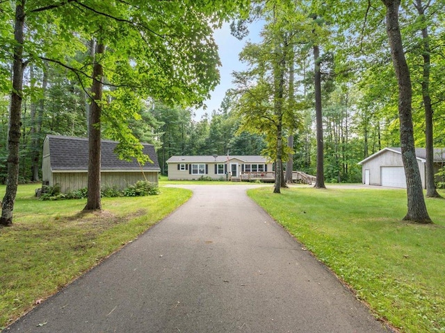 view of front of property with an outbuilding, a garage, a front lawn, and roof with shingles