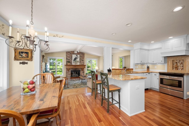 2135 Shadyview Ln N, Plymouth, MN 55447 - kitchen featuring stainless steel range with electric stovetop, a brick fireplace, a chandelier, light wood-style floors, and white cabinets