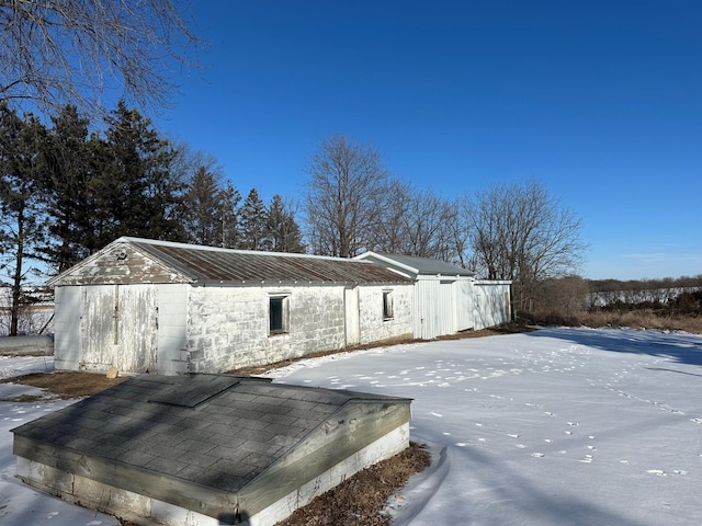 snow covered property with concrete block siding and metal roof