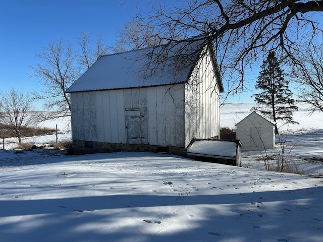 snow covered structure with an outbuilding