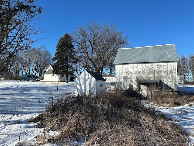 yard covered in snow with an outbuilding and a barn