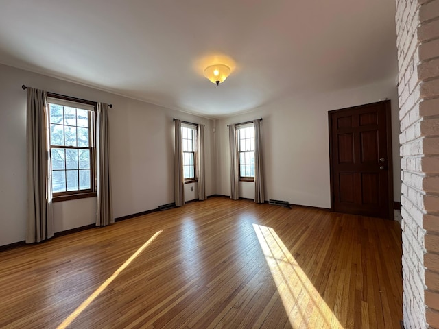 empty room featuring visible vents, light wood-style flooring, and baseboards