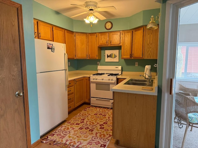 kitchen featuring a sink, light countertops, a ceiling fan, white appliances, and brown cabinets