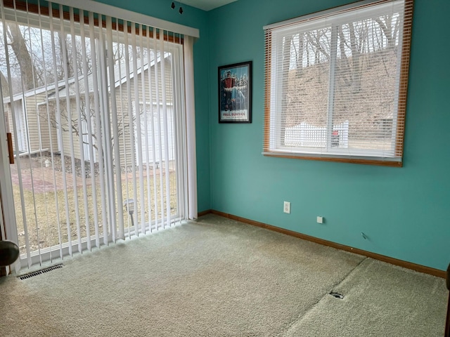 unfurnished room featuring carpet flooring, visible vents, and baseboards