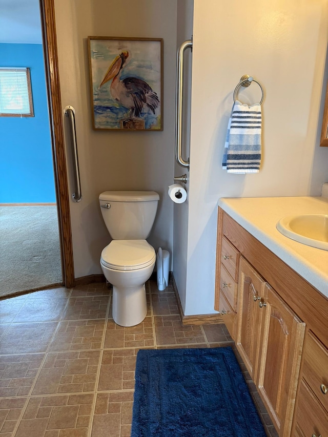 bathroom featuring toilet, baseboards, and vanity