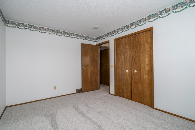 unfurnished bedroom featuring a textured ceiling, carpet floors, a closet, and baseboards