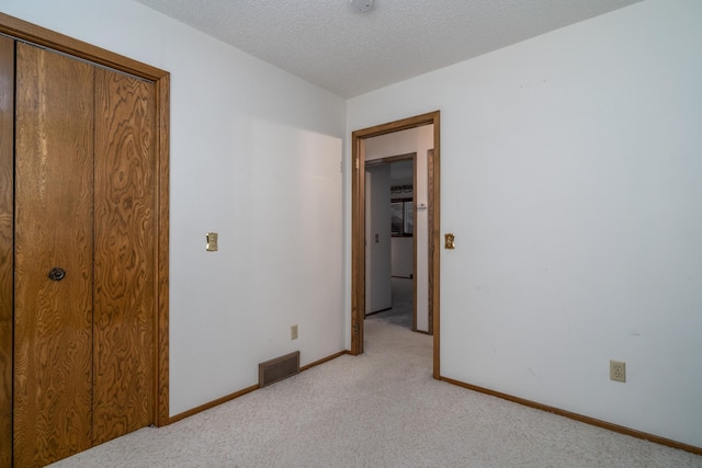 unfurnished bedroom with light carpet, baseboards, visible vents, and a textured ceiling