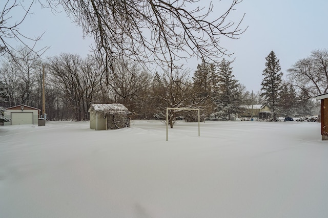 snowy yard featuring a detached garage and an outbuilding