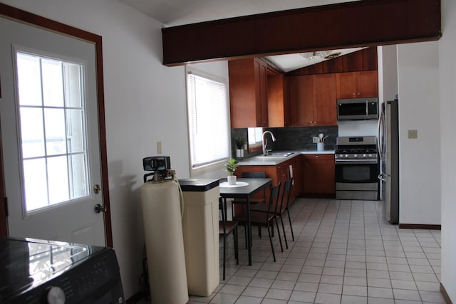 kitchen featuring light tile patterned floors, decorative backsplash, stainless steel appliances, light countertops, and a sink