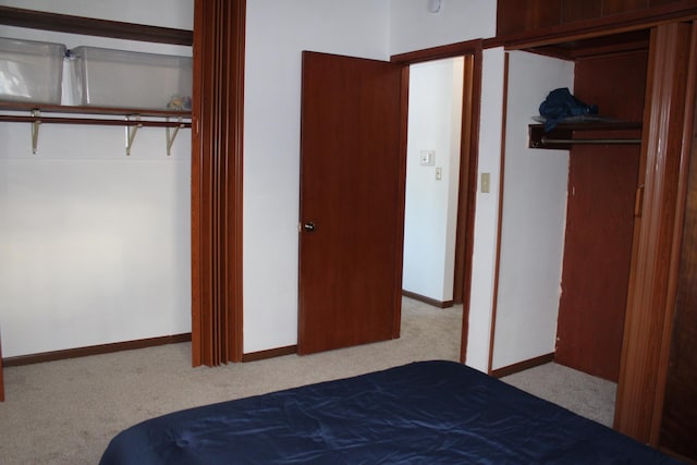 unfurnished bedroom with light carpet, a closet, and baseboards