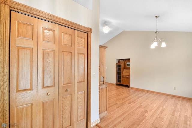 hall featuring lofted ceiling, an inviting chandelier, baseboards, and light wood finished floors