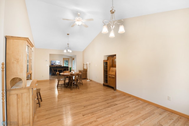 dining area featuring light wood-style flooring, ceiling fan with notable chandelier, baseboards, and high vaulted ceiling