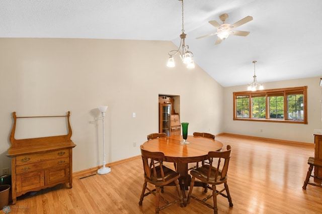 dining space featuring baseboards, ceiling fan with notable chandelier, light wood-style flooring, and vaulted ceiling