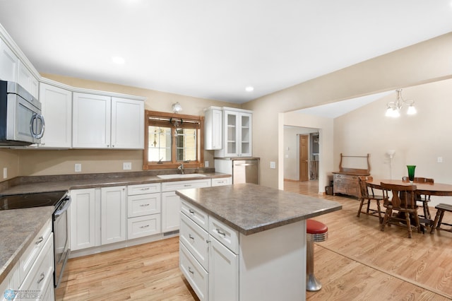 kitchen featuring a sink, stainless steel appliances, a kitchen breakfast bar, and light wood-style floors