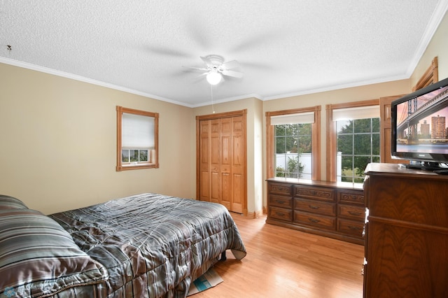 bedroom with light wood-style flooring, ceiling fan, a closet, a textured ceiling, and crown molding