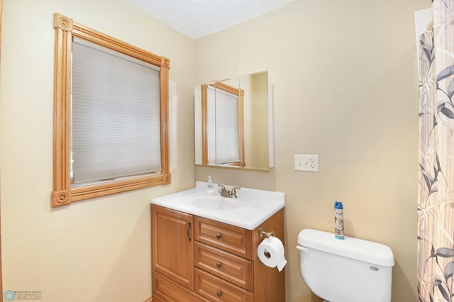 bathroom with toilet, vanity, and a textured ceiling