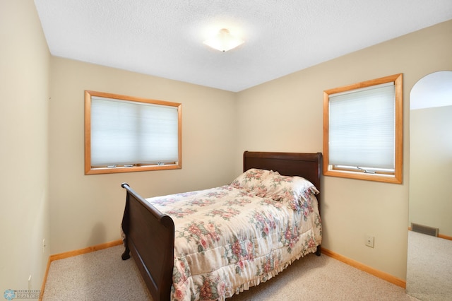 bedroom with visible vents, baseboards, carpet floors, and a textured ceiling