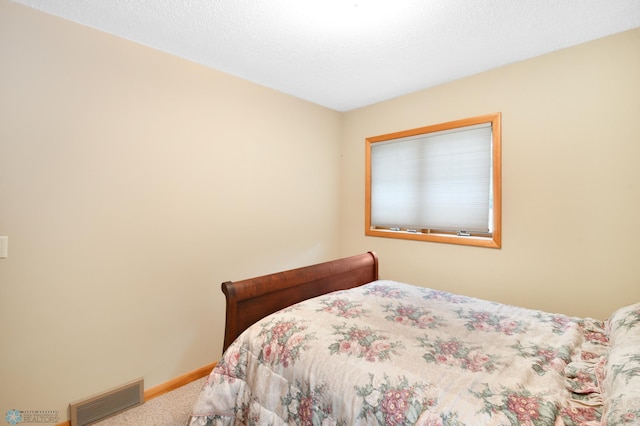 carpeted bedroom featuring baseboards, visible vents, and a textured ceiling