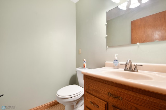 half bath featuring tile patterned floors, toilet, vanity, and baseboards