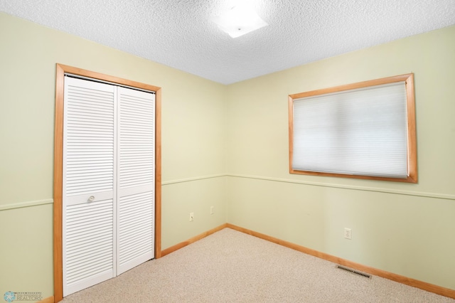 unfurnished bedroom with a closet, visible vents, a textured ceiling, and carpet