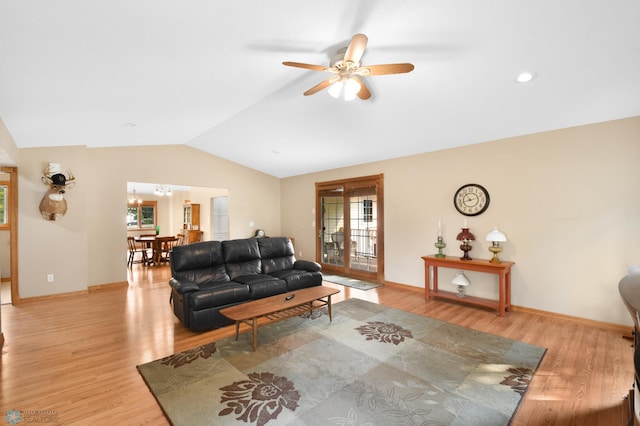 living area with baseboards, light wood-type flooring, lofted ceiling, and a ceiling fan