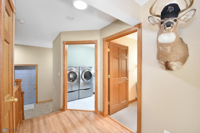 clothes washing area with laundry area, wood finished floors, washing machine and dryer, and baseboards