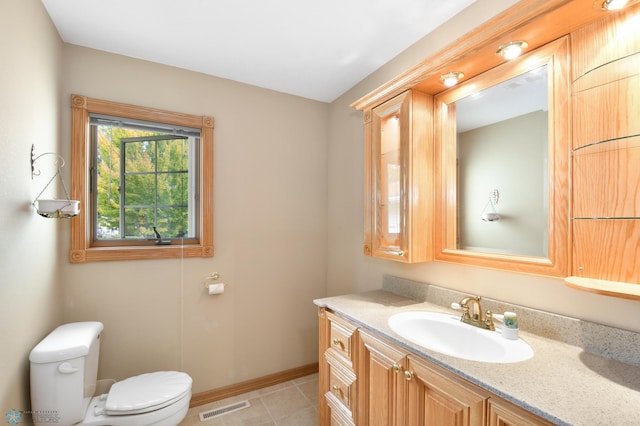 half bathroom with vanity, baseboards, visible vents, tile patterned flooring, and toilet