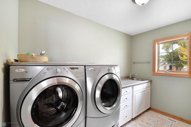 laundry area featuring visible vents, baseboards, washing machine and dryer, cabinet space, and a sink