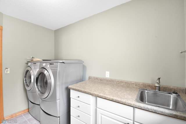 washroom with independent washer and dryer, a sink, a textured ceiling, cabinet space, and light tile patterned floors