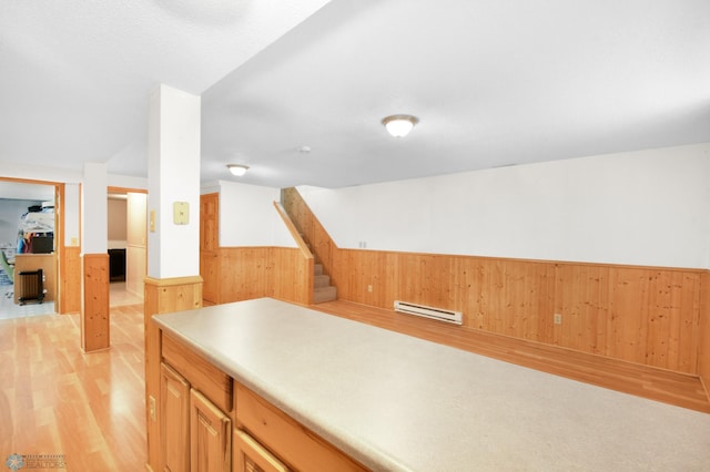 interior space featuring light wood finished floors, wainscoting, light countertops, and wood walls