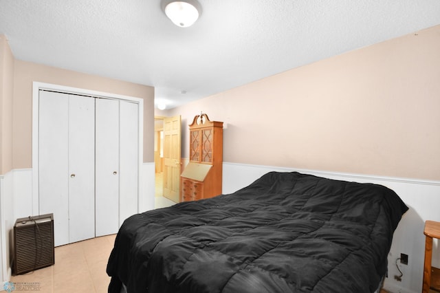 bedroom with a closet, a textured ceiling, and light tile patterned flooring