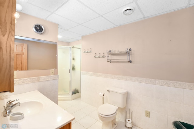 full bathroom featuring toilet, a stall shower, a drop ceiling, tile patterned flooring, and vanity