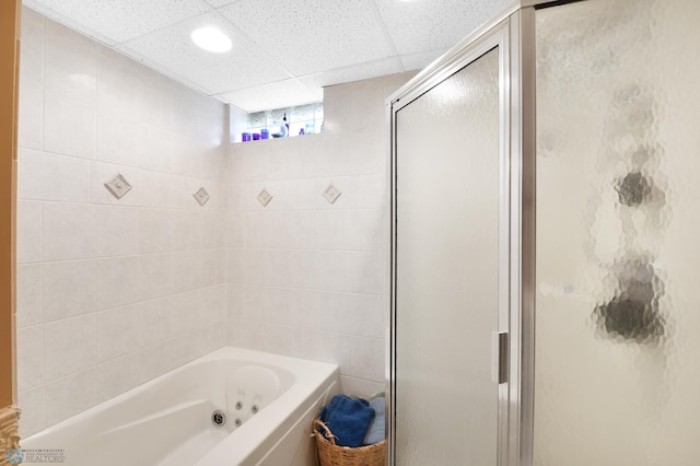 full bathroom featuring a drop ceiling, a tub with jets, and a shower stall