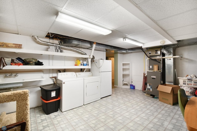 finished below grade area featuring concrete block wall, light floors, freestanding refrigerator, and washer and clothes dryer