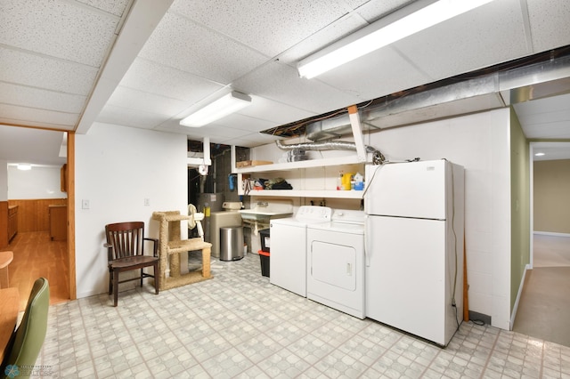 finished basement with a drop ceiling, light floors, washer and dryer, and freestanding refrigerator